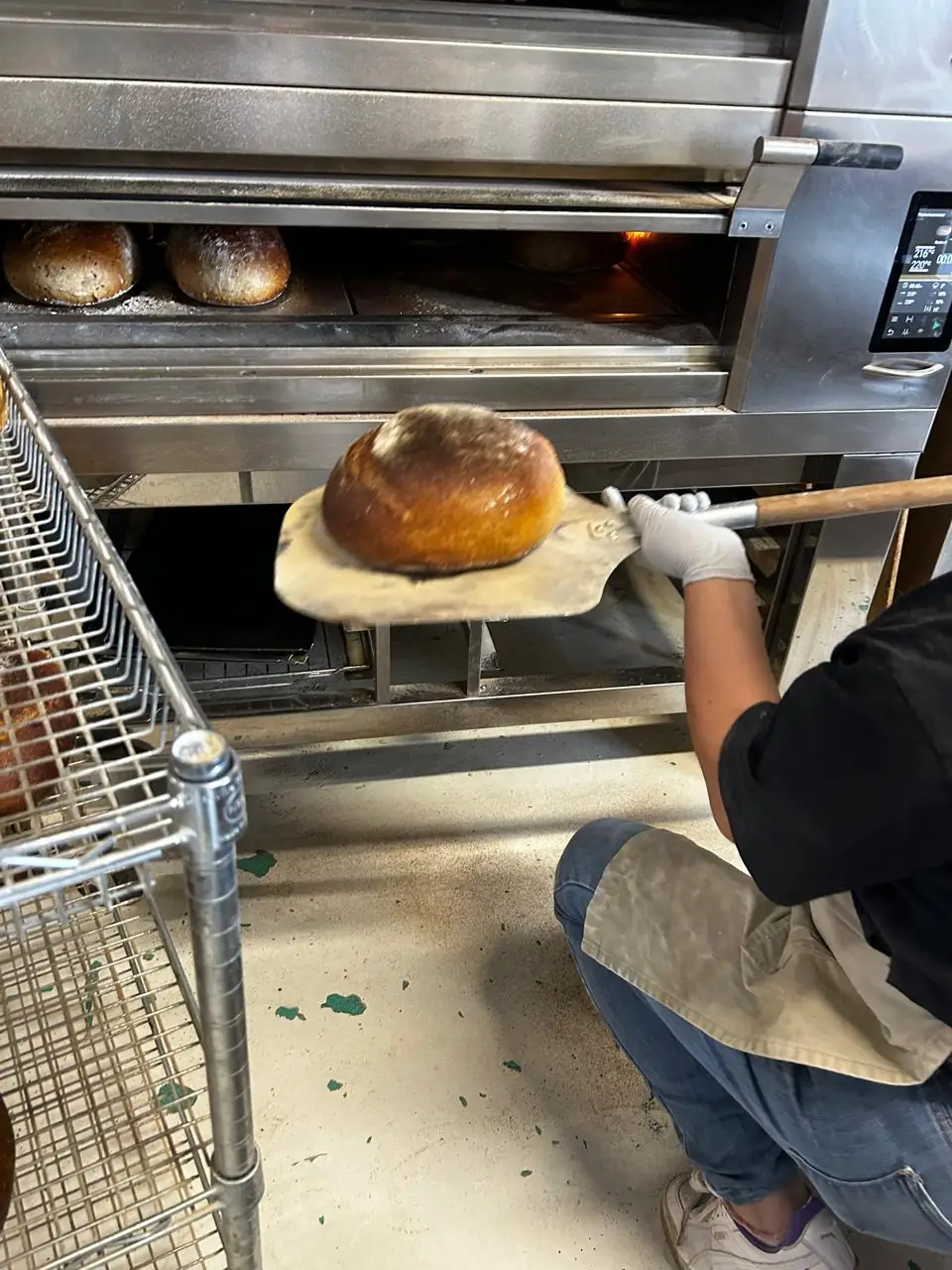 Panadero cargando el horno de piso con la pala en la panadería Pan de Elia